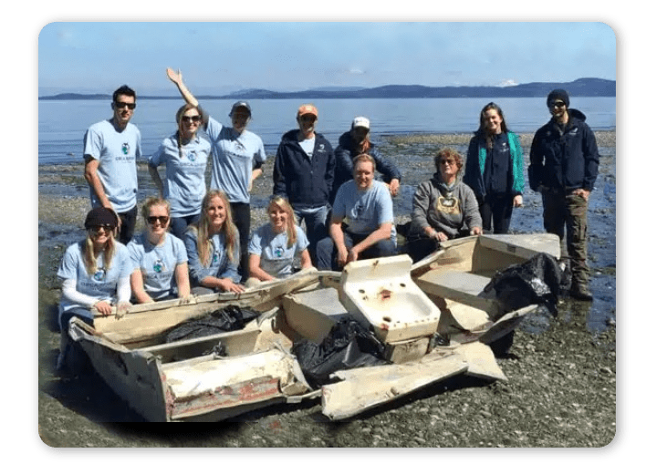 Group of people posing with collected trash on a beach.