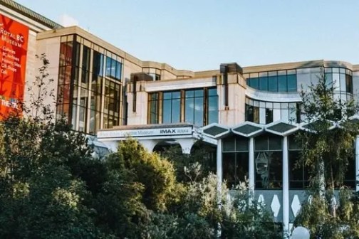 Modern building with trees and large red banner on facade.